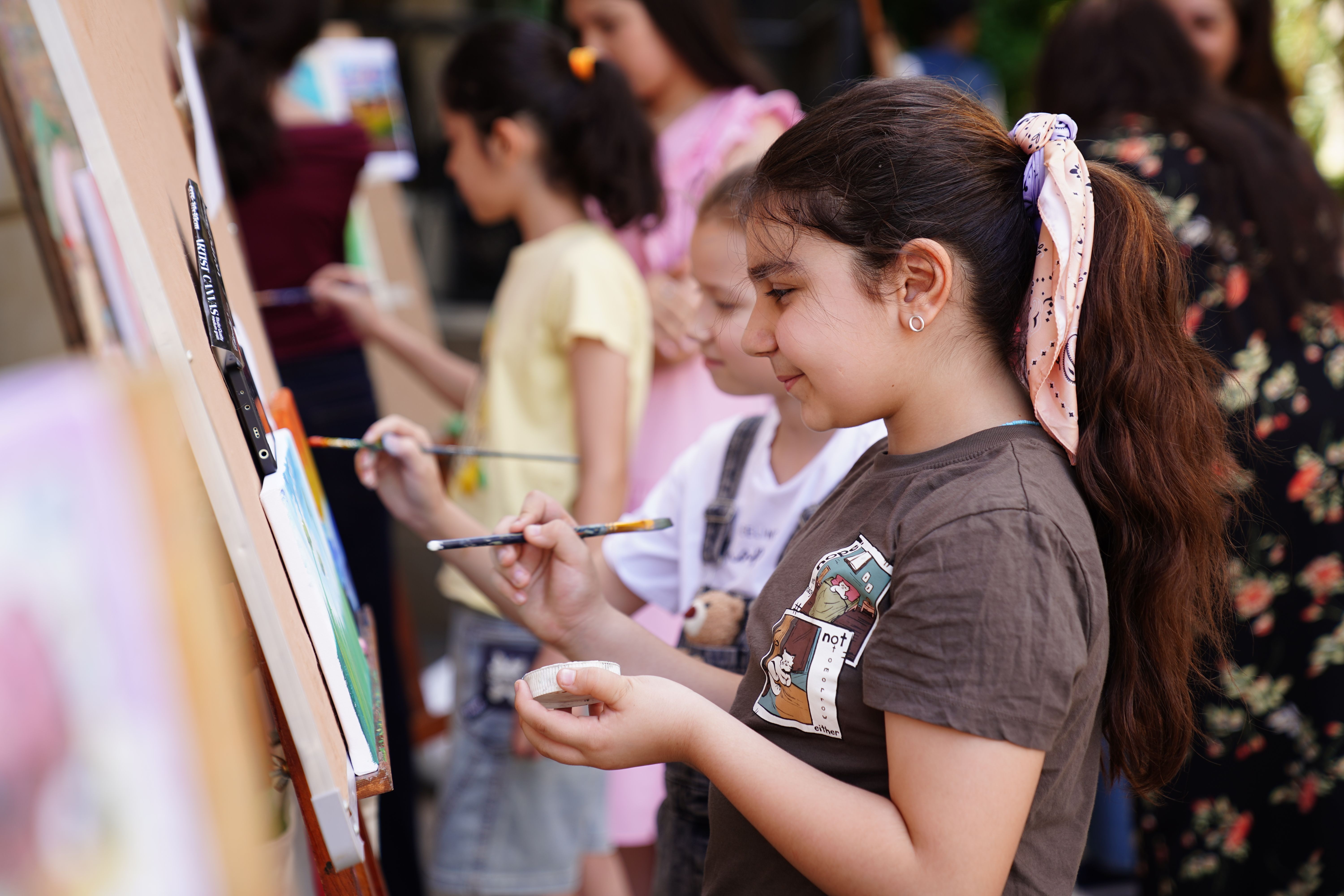 Children painting together outdoors in an art class